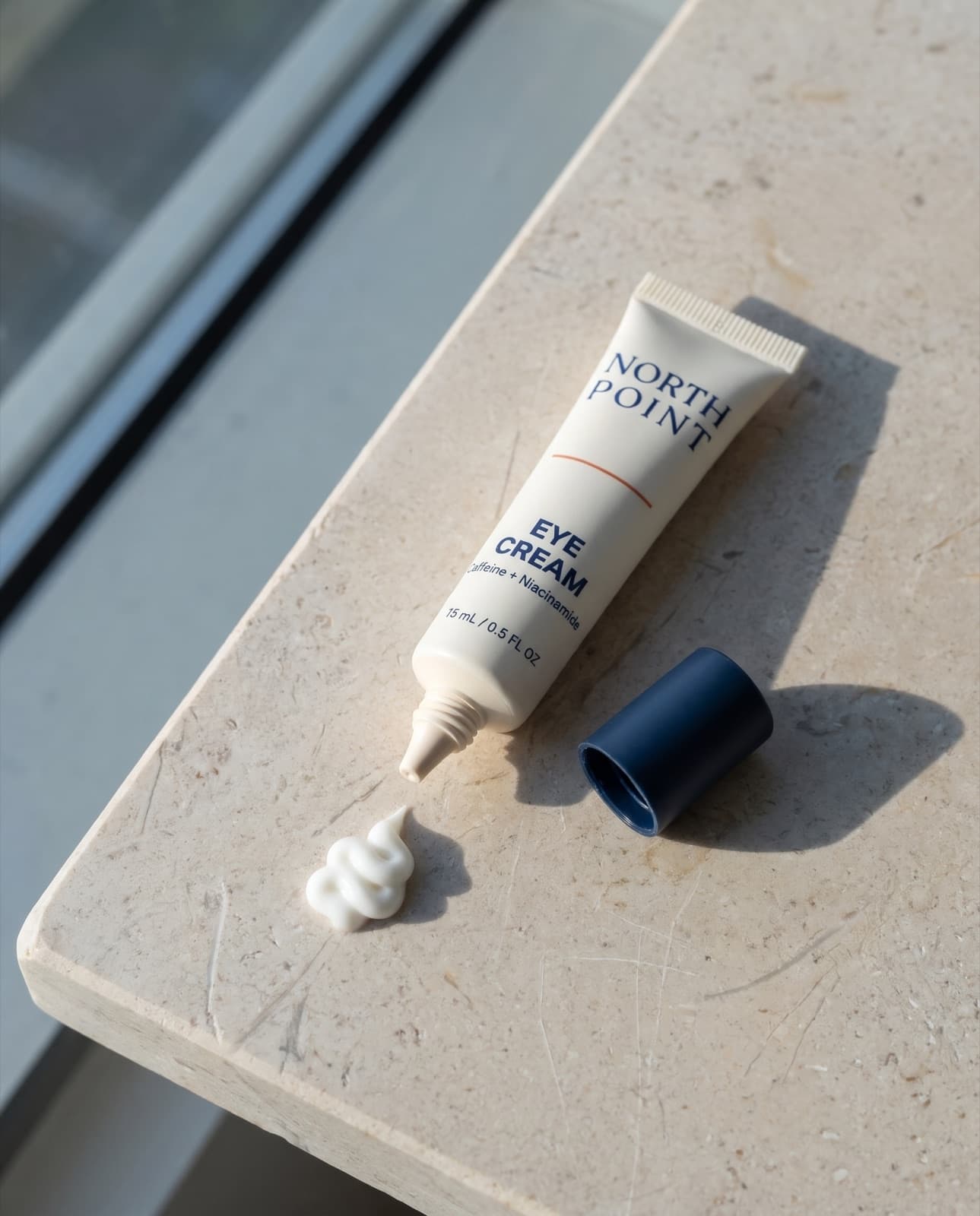 The Eye Cream tube with a swirl of cream piped onto a limestone ledge